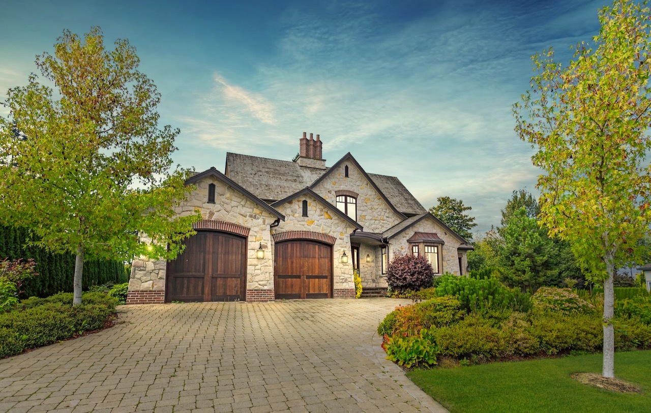 The front of a large, luxury suburban home with an oversized driveway and two garages